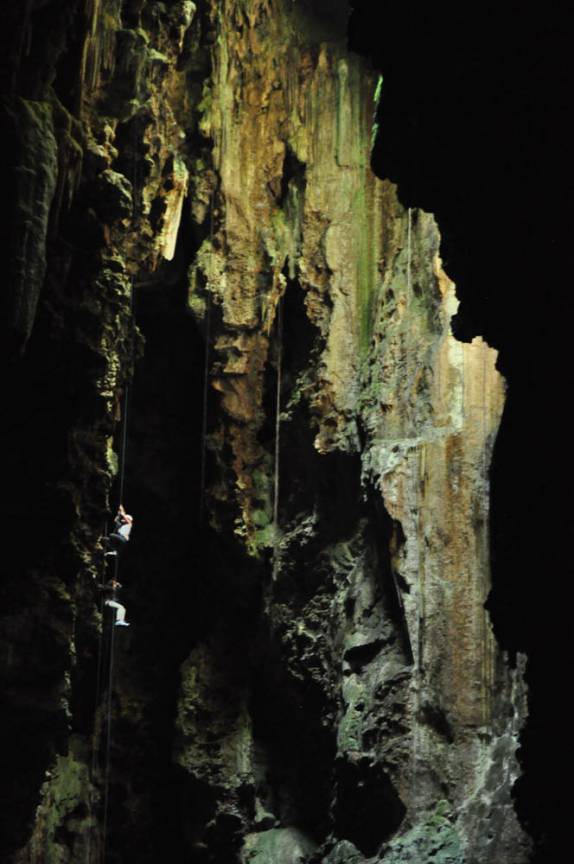 Pessoas fazendo rapel para sair da caverna ficam minúsculas perto do gigantismo do Abismo de Anhumas, em Bonito, no Mato Grosso do Sul